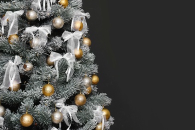 Photo of Decorated Christmas tree against black background, closeup