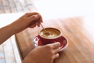 Woman with cup of fresh aromatic coffee at table, closeup