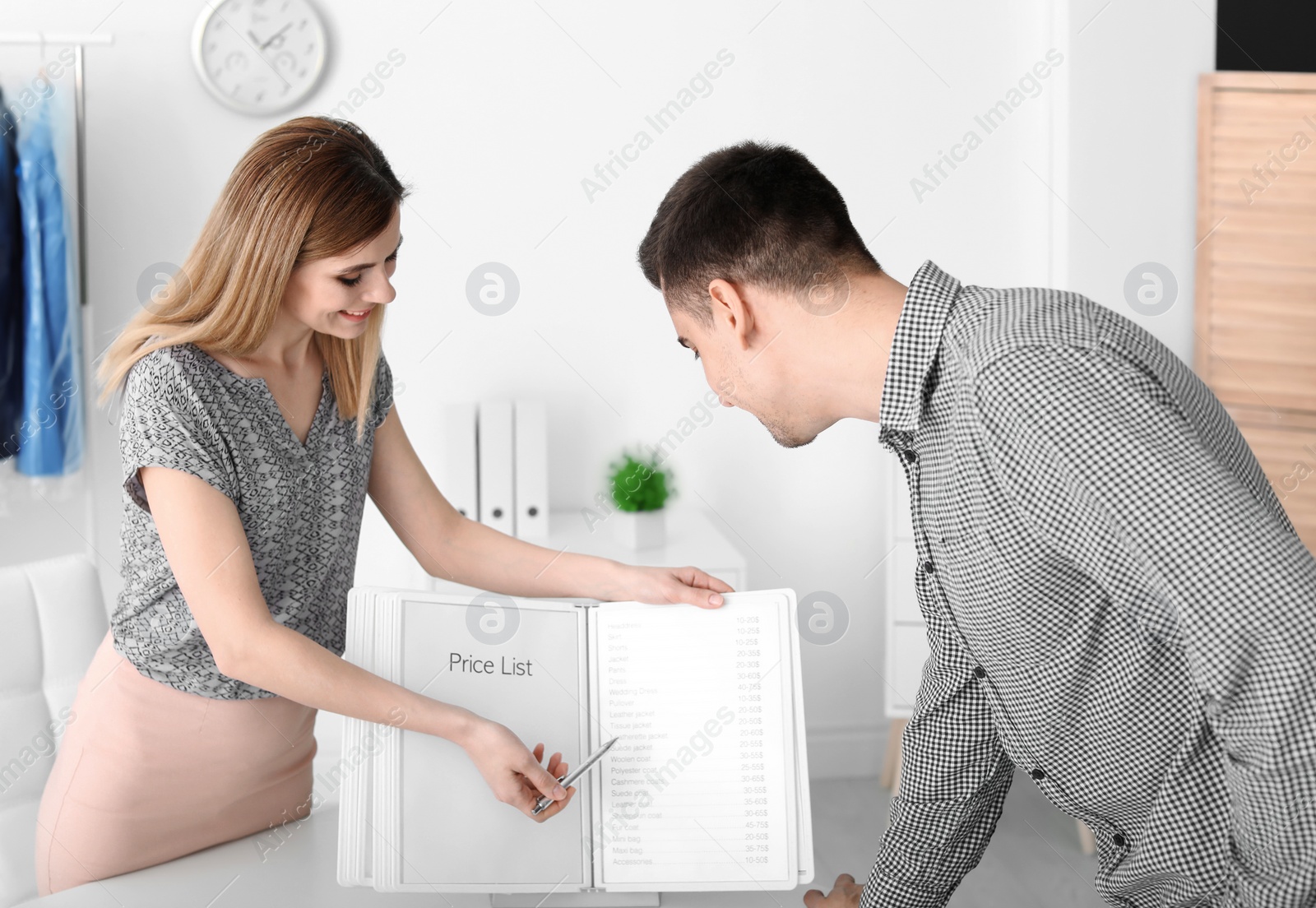 Photo of Female dry-cleaner's worker showing price list to customer