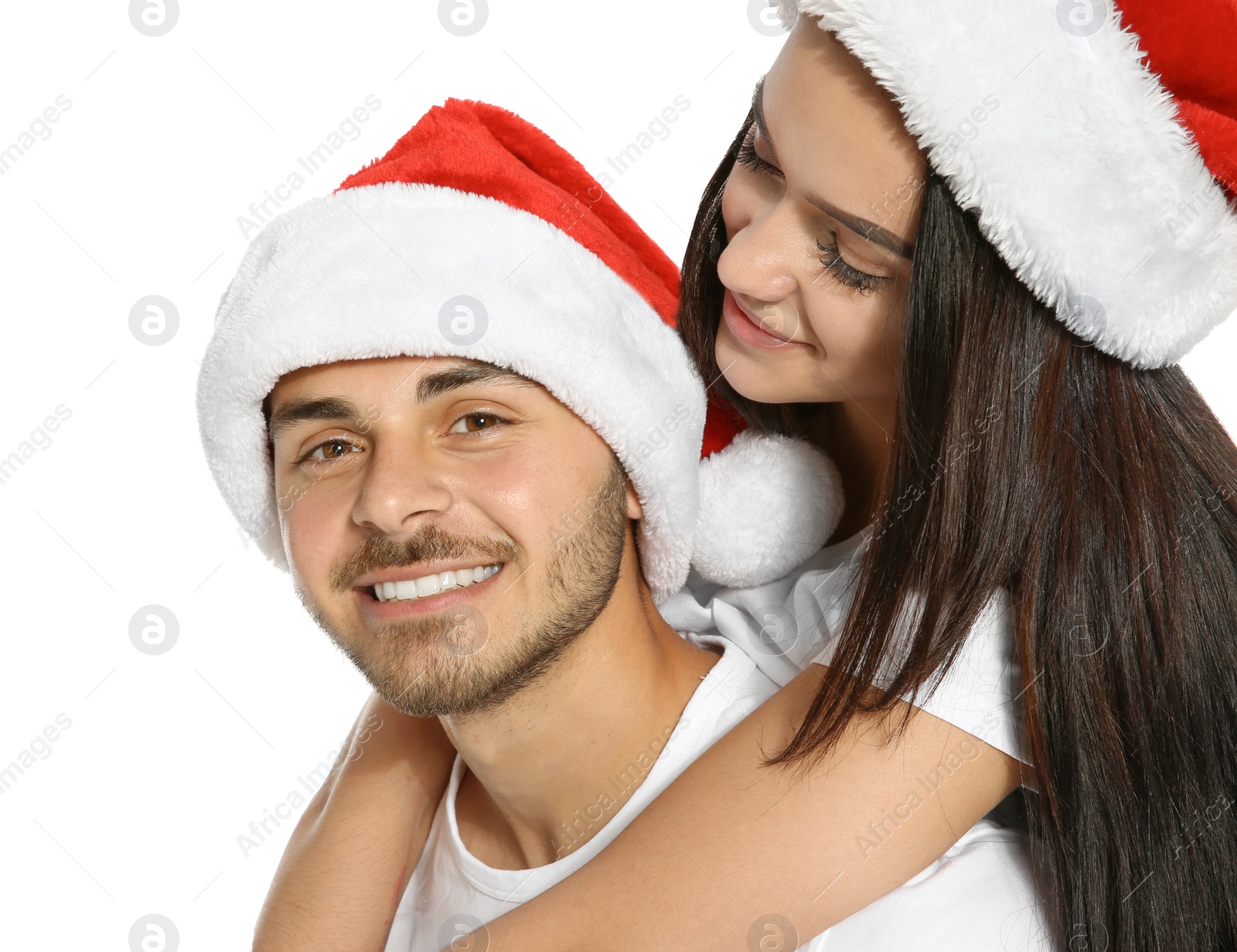 Photo of Young happy couple with Santa hats on white background. Christmas celebration