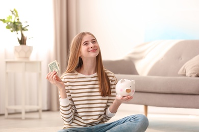 Teen girl with piggy bank and money at home