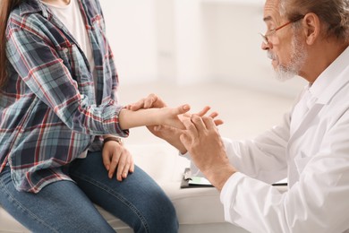 Photo of Orthopedist examining patient with injured hand in clinic, closeup