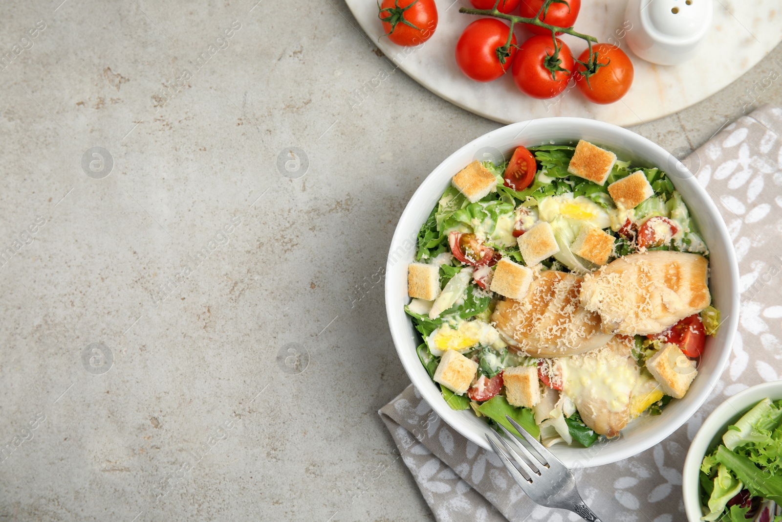 Photo of Delicious fresh Caesar salad in bowl on light grey table, flat lay. Space for text