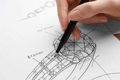 Photo of Jeweler drawing sketch of elegant ring on paper, closeup