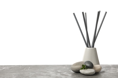 Photo of Spa stones, green branch and reed air freshener on grey table against white background. Space for text