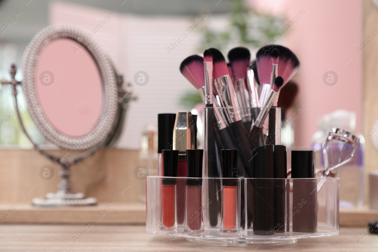 Photo of Organizer with cosmetic products for makeup on table near mirror