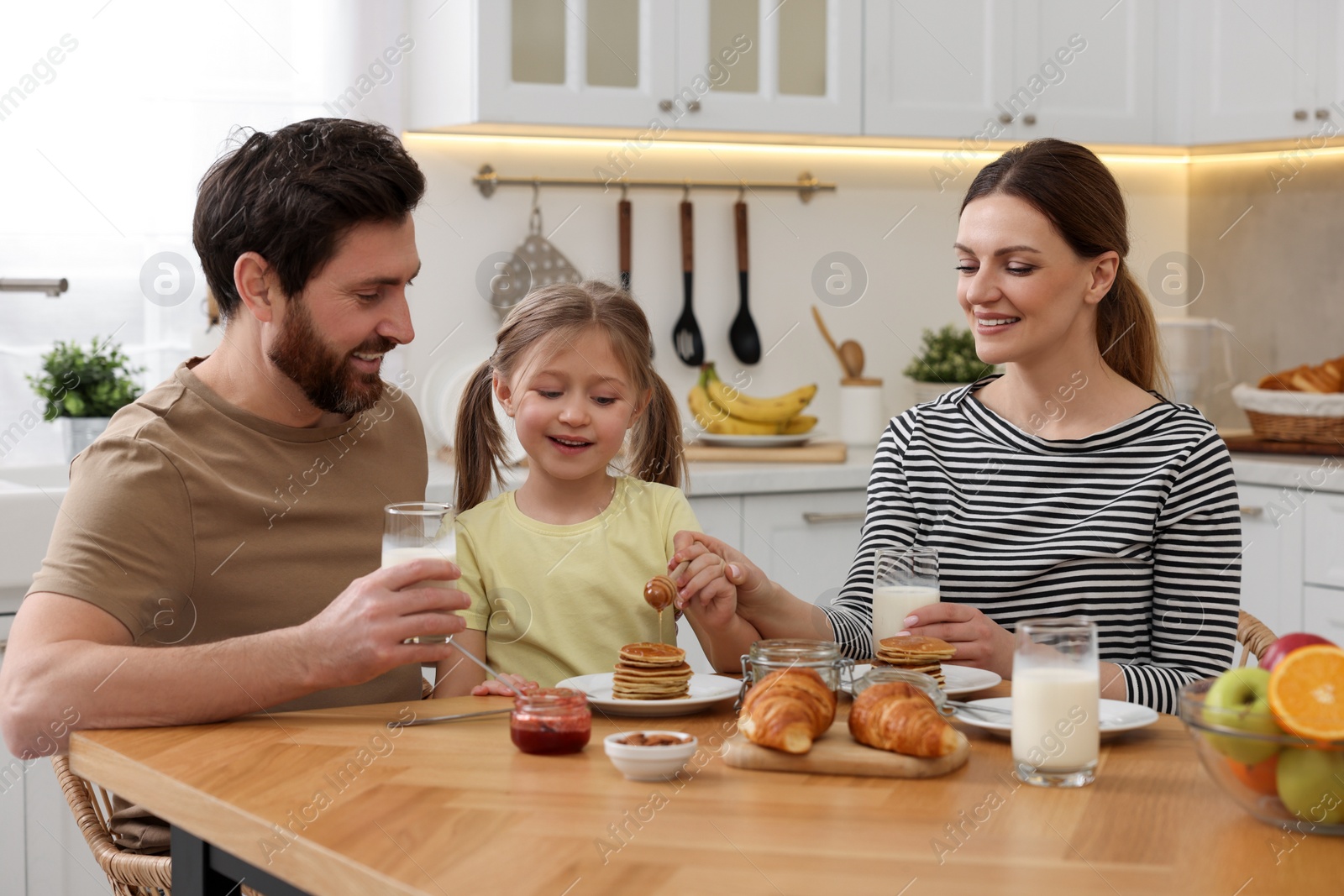 Photo of Happy family having breakfast at table in kitchen