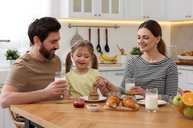 Photo of Happy family having breakfast at table in kitchen