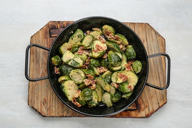 Photo of Delicious cooked Brussels sprouts with bacon in pan on white table, top view