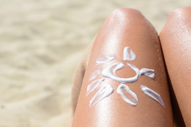 Photo of Sun drawn with sunscreen on woman's leg at beach, closeup. Space for text