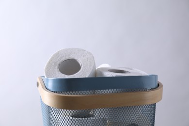 Toilet paper rolls in basket against light grey wall