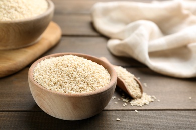 Photo of Sesame seeds in bowl on wooden table. Space for text