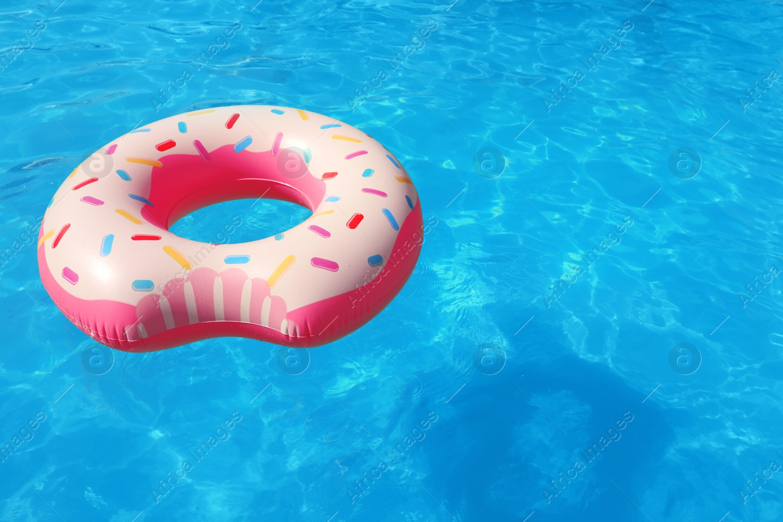 Photo of Inflatable ring floating in swimming pool on sunny day. Space for text