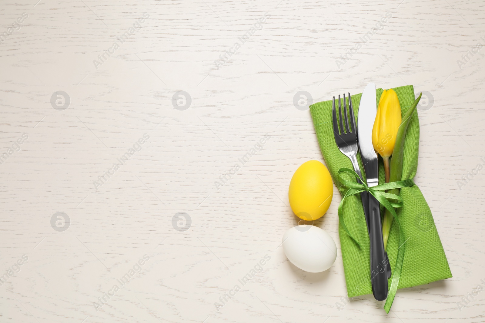 Photo of Cutlery set and eggs on white wooden table, flat lay with space for text. Easter celebration