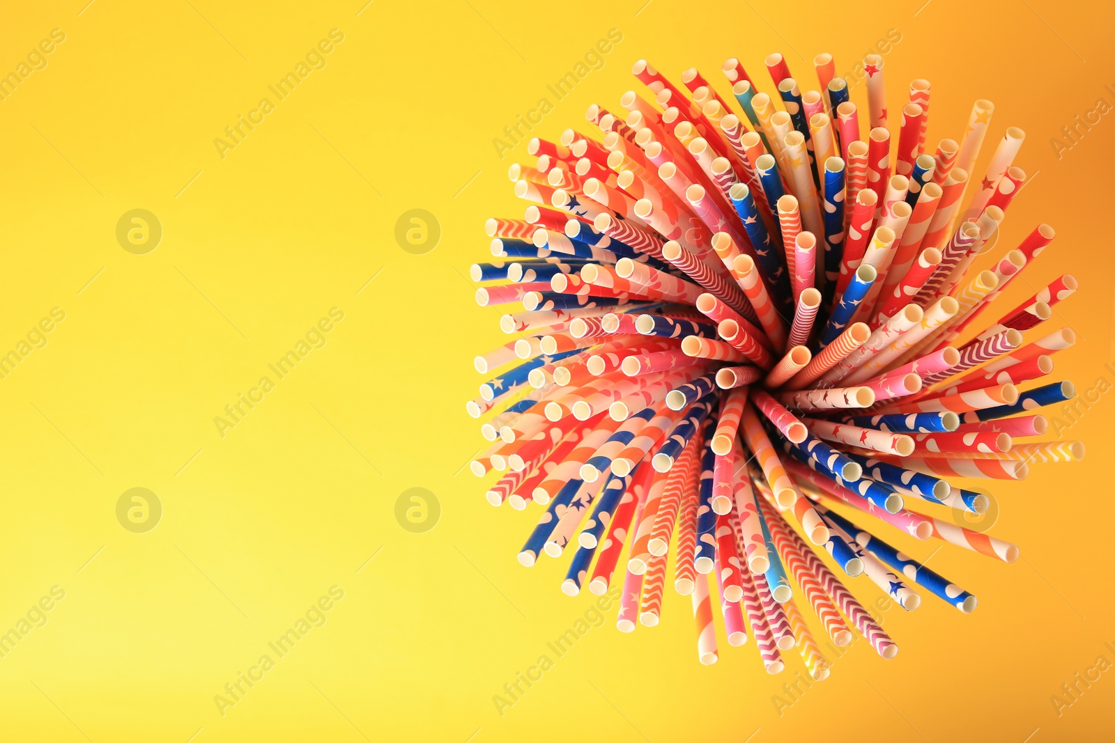 Photo of Many paper drinking straws on yellow background, top view. Space for text