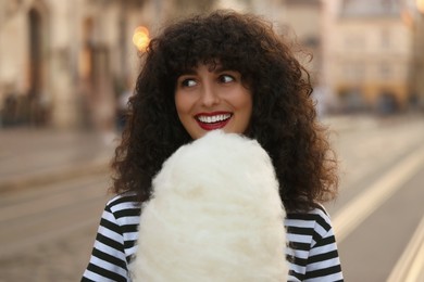 Photo of Portrait of happy woman with cotton candy on city street
