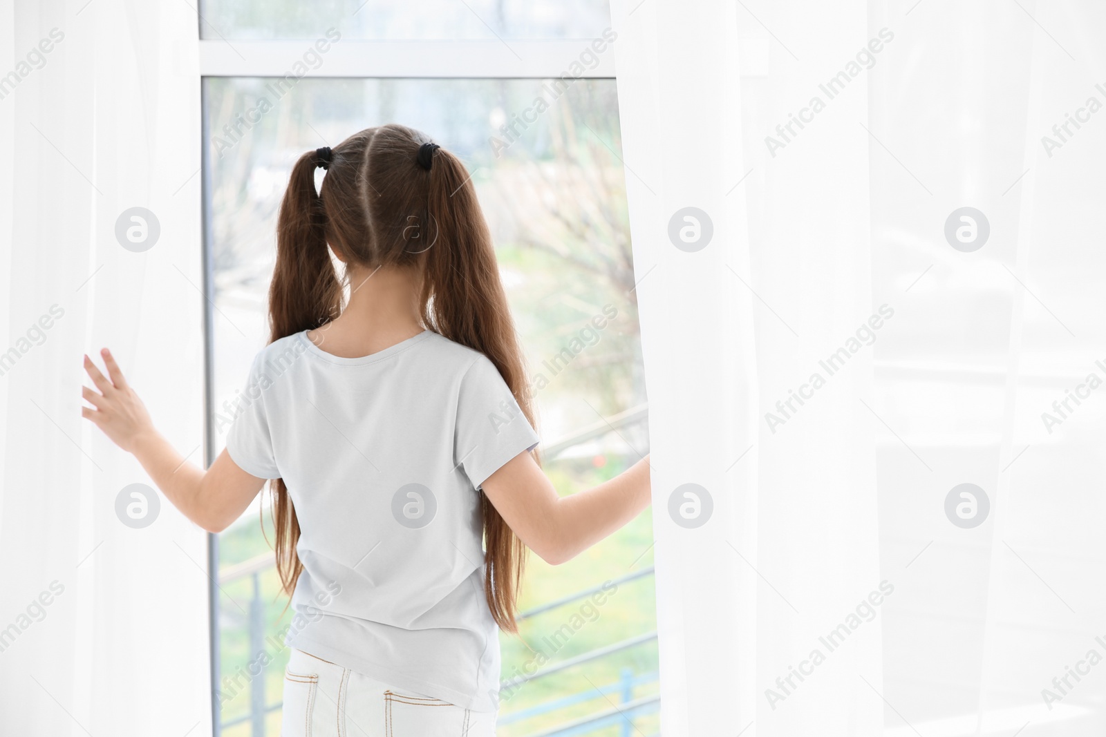Photo of Little girl standing near window. Autism concept