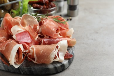 Photo of Pile of tasty prosciutto on light grey table, closeup