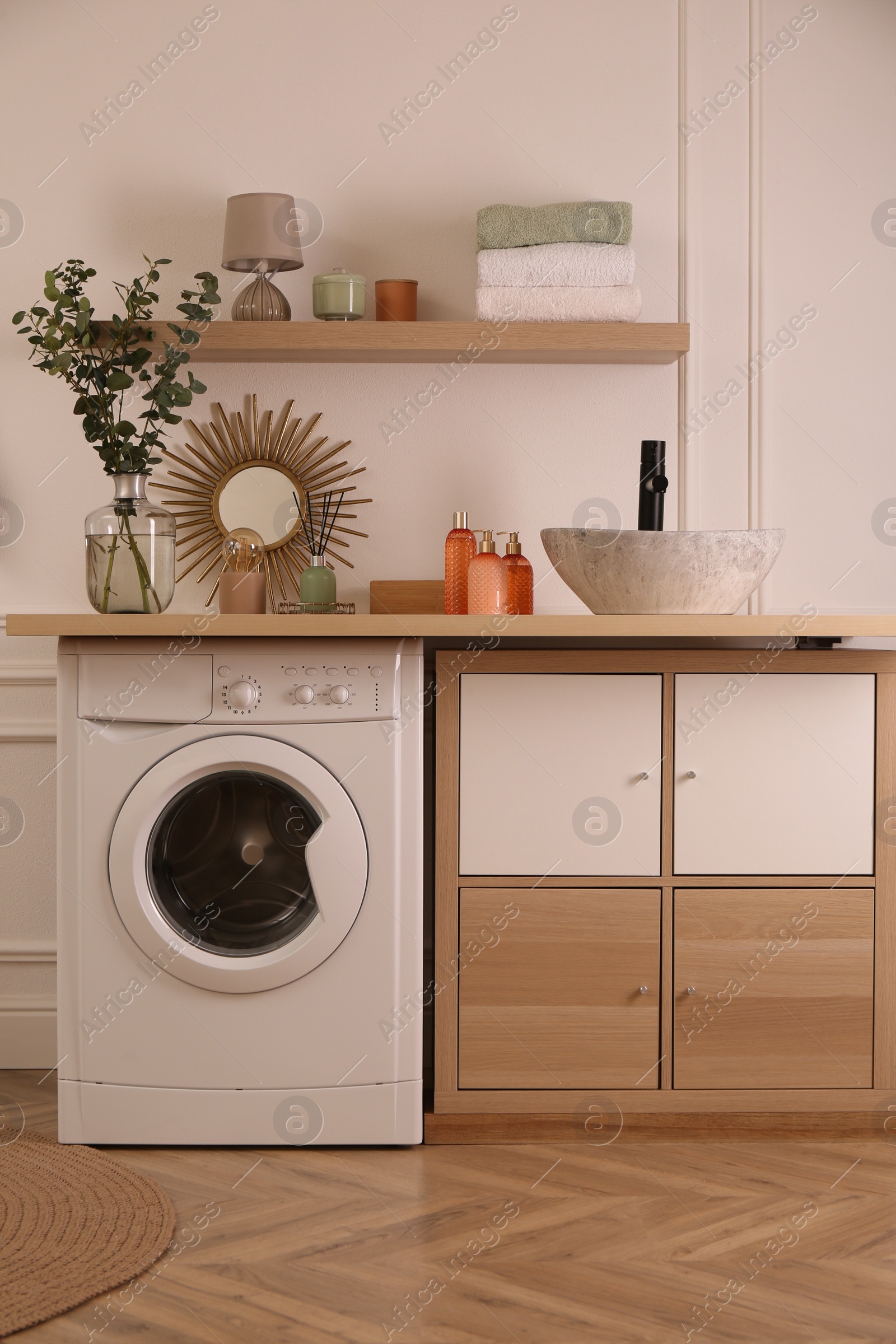 Photo of Laundry room interior with modern washing machine and stylish vessel sink on countertop