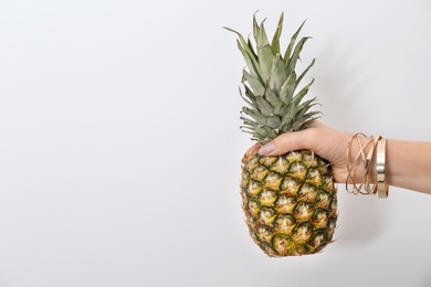 Photo of Woman holding pineapple on light background, closeup