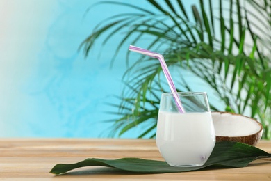 Photo of Composition with glass of coconut water on wooden table against blue background. Space for text