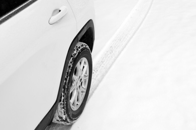 Modern car leaving tire track on snowy road, closeup view
