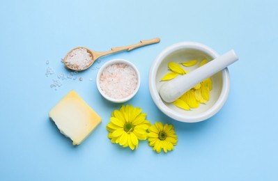 Photo of Flat lay composition with beeswax, bath salt and flowers on light blue background
