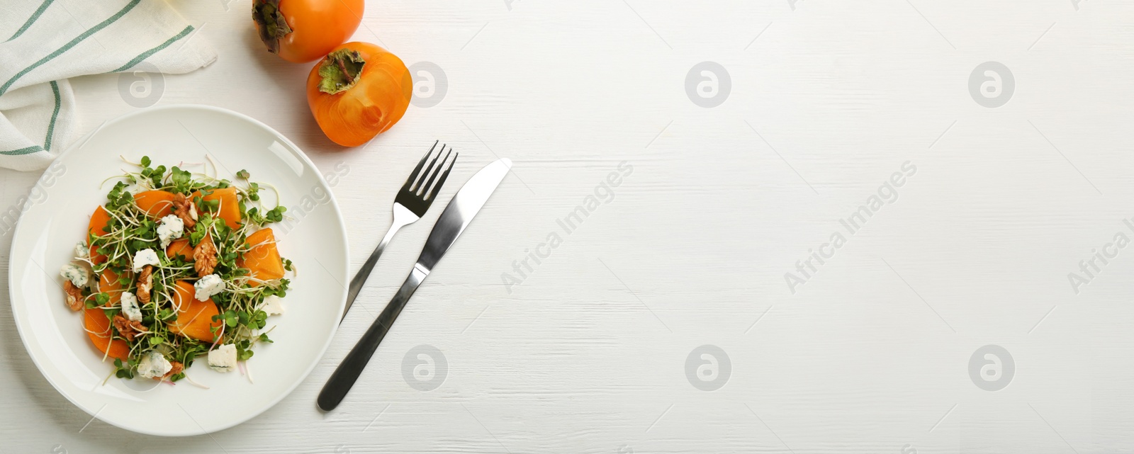 Image of Delicious persimmon salad served on white wooden table, flat lay with space for text. Banner design