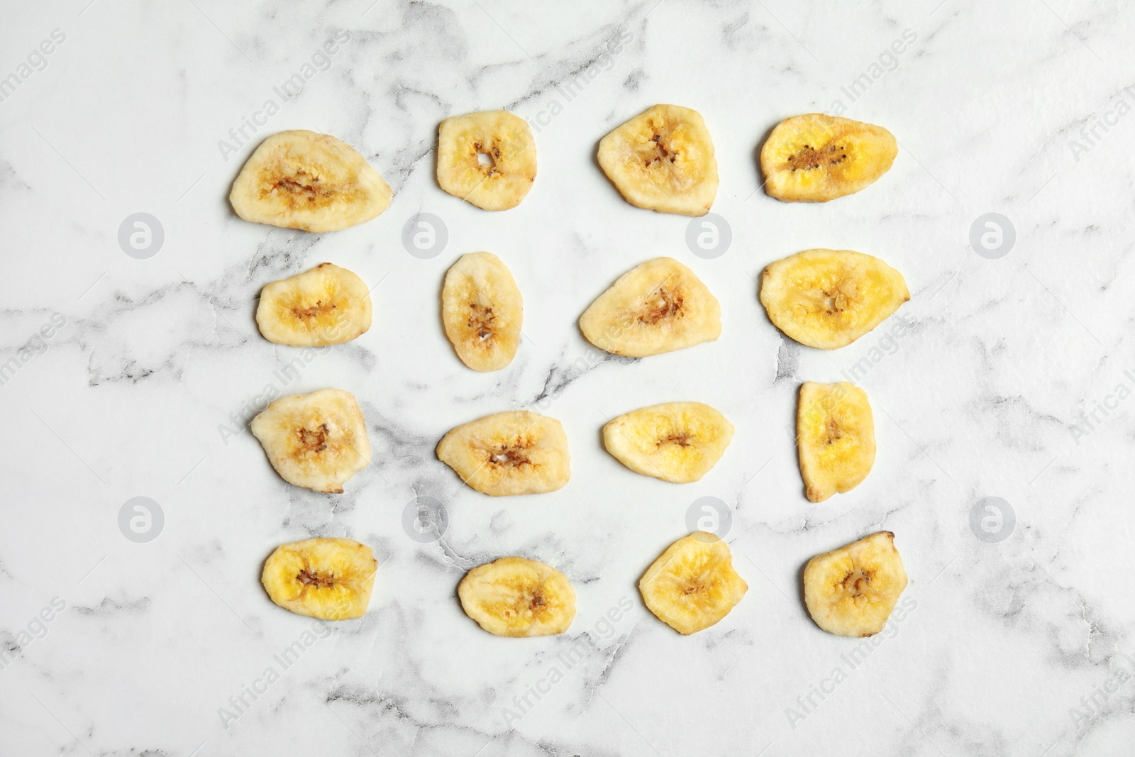 Photo of Flat lay composition with banana slices on marble table. Dried fruit as healthy snack
