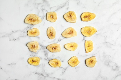 Photo of Flat lay composition with banana slices on marble table. Dried fruit as healthy snack