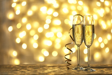 Glasses of champagne on table against blurred lights. Space for text