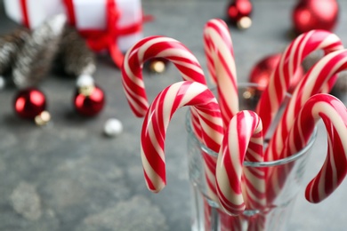 Photo of Many sweet candy canes in glass on table, closeup. Traditional Christmas treat