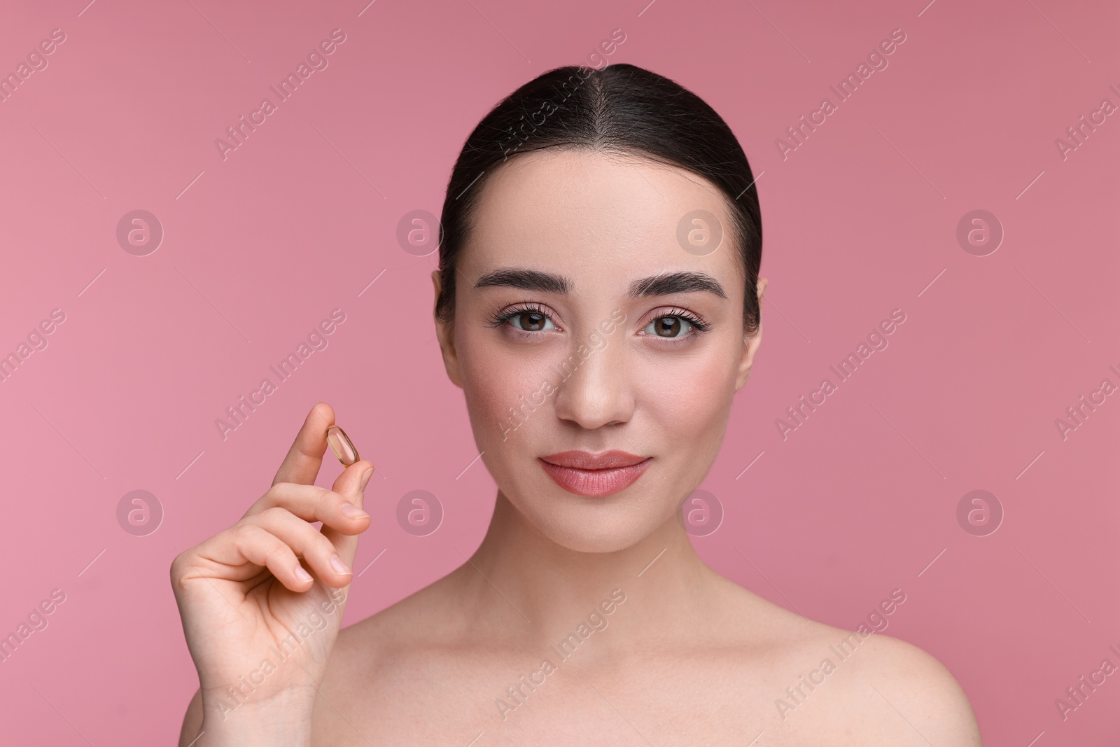 Photo of Beautiful young woman with vitamin pill on pink background