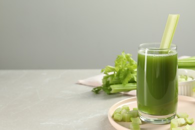 Glass of delicious celery juice and vegetables on grey table, closeup. Space for text