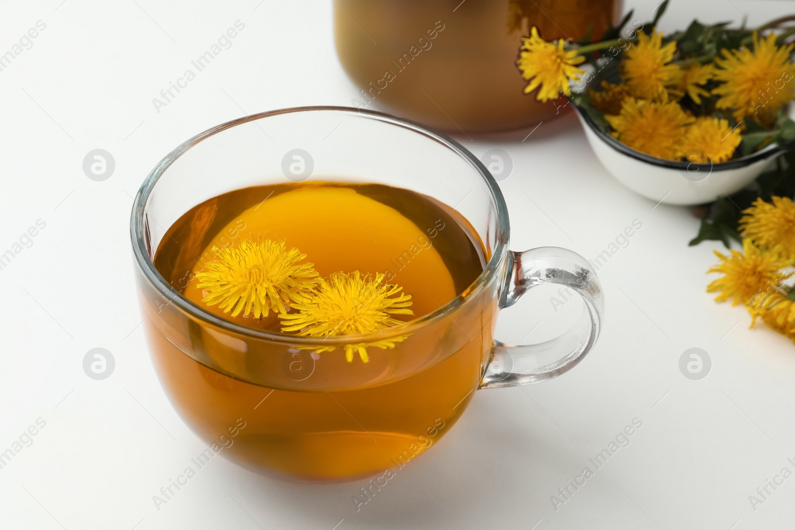 Photo of Delicious fresh tea and beautiful dandelion flowers on white background