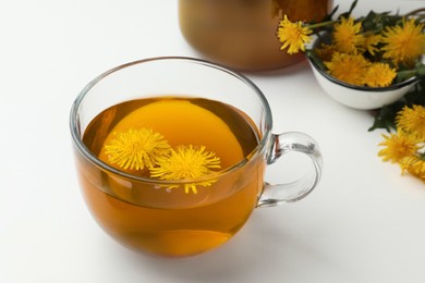 Photo of Delicious fresh tea and beautiful dandelion flowers on white background