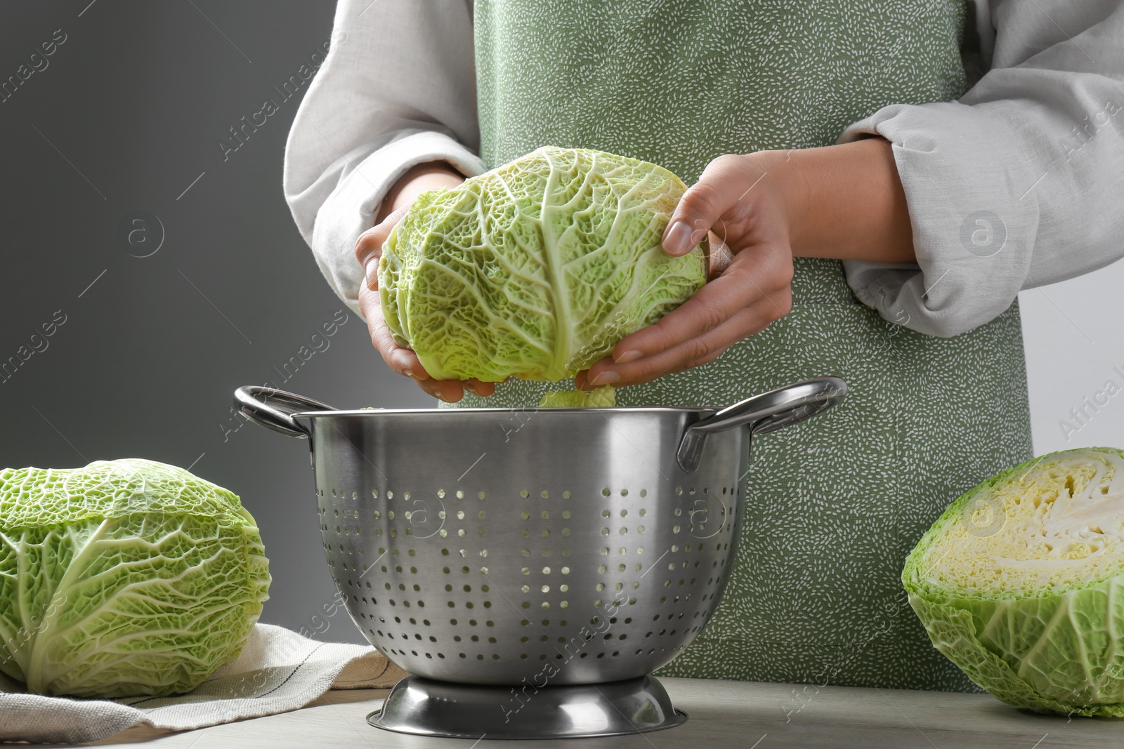 Photo of Woman with fresh savoy cabbage at wooden table, closeup