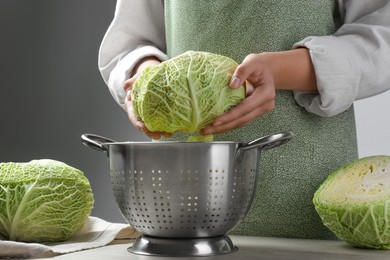 Woman with fresh savoy cabbage at wooden table, closeup