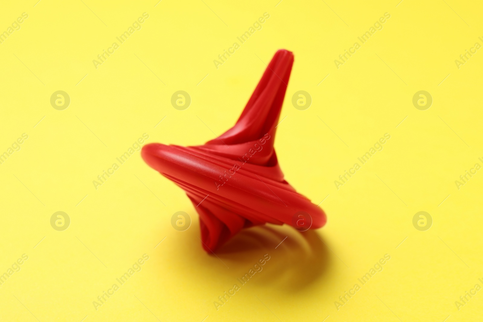 Photo of One red spinning top on yellow background, closeup