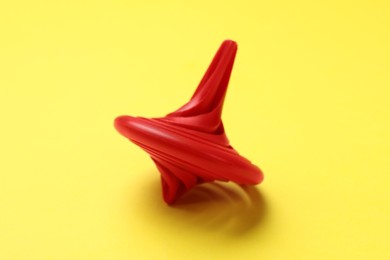 One red spinning top on yellow background, closeup