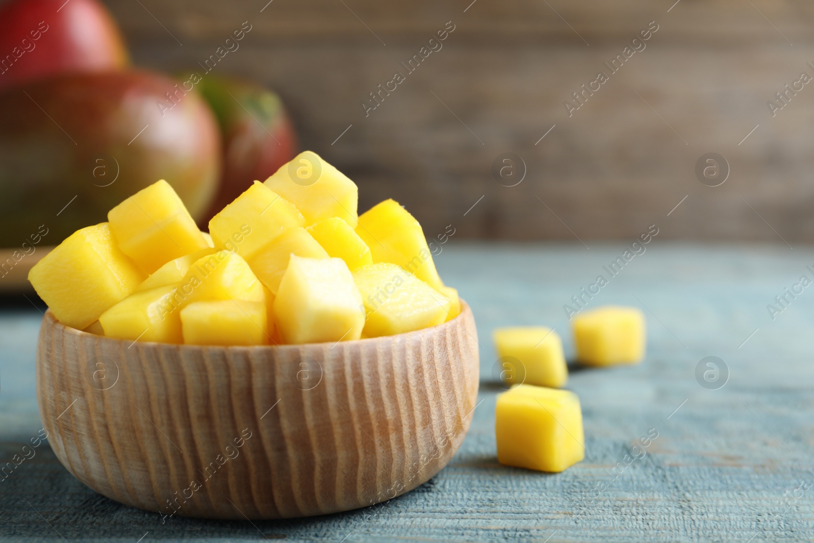 Photo of Cubes of fresh ripe mango in bowl on wooden table