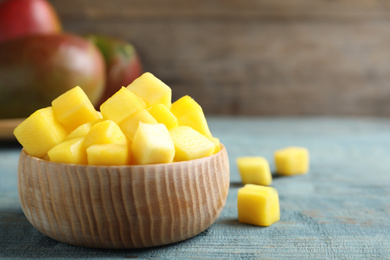 Cubes of fresh ripe mango in bowl on wooden table