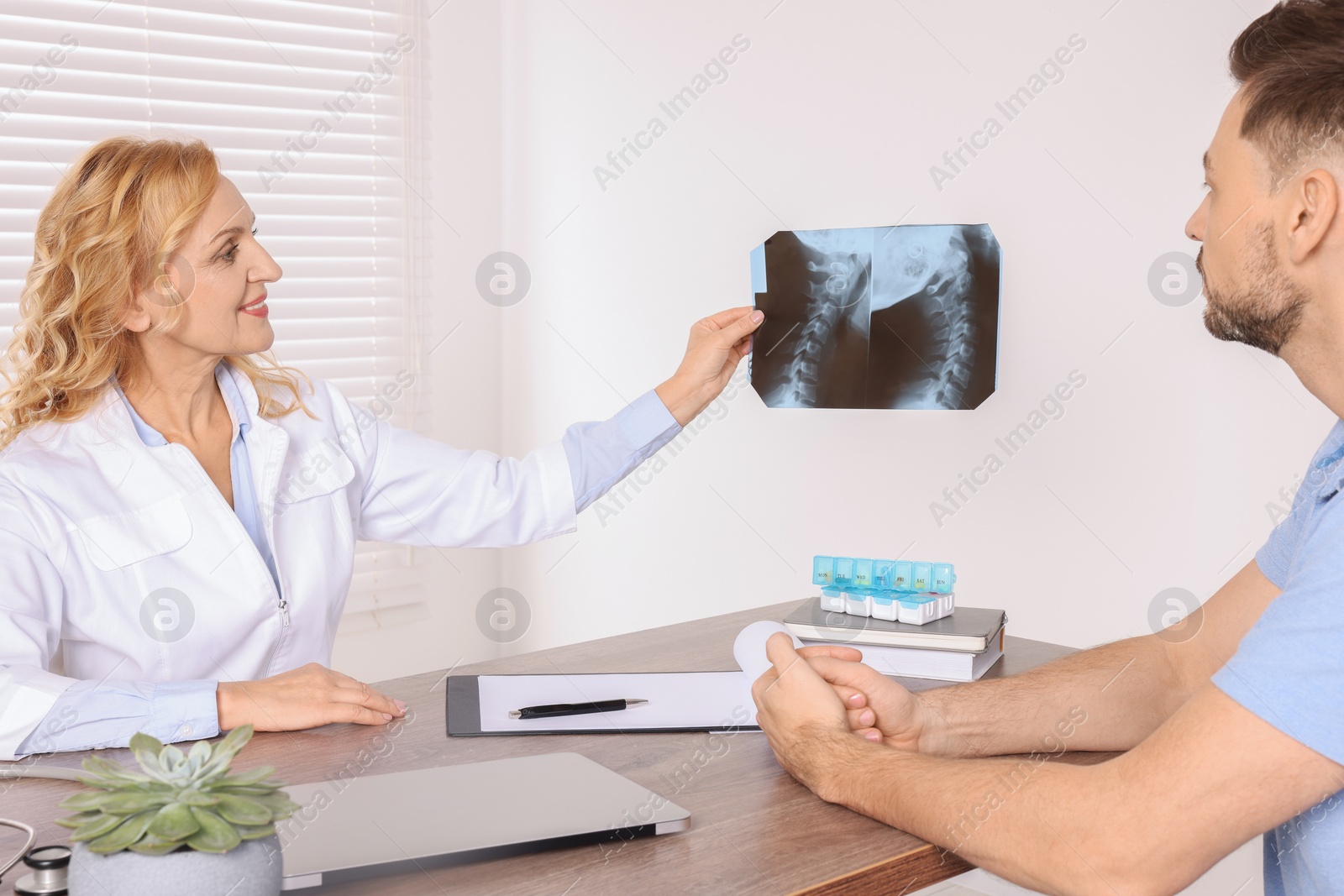 Photo of Doctor with X-ray image consulting patient in clinic