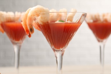 Photo of Tasty shrimp cocktail with sauce in glasses on table, closeup