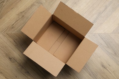 Photo of Empty open cardboard box on floor, top view