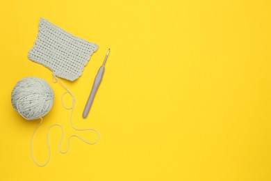 Photo of Knitting and crochet hook on yellow background, flat lay. Space for text