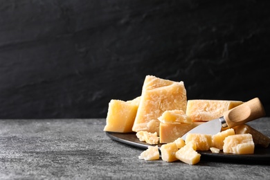 Parmesan cheese with board and knife on grey table. Space for text