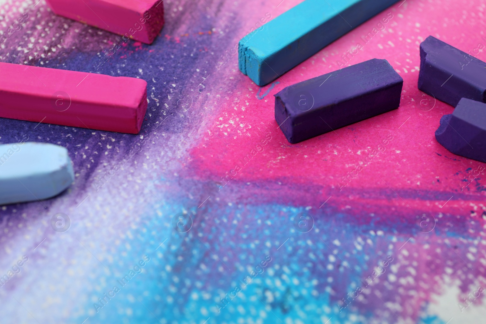 Photo of Colorful pastel chalks on abstract painting, closeup. Drawing materials