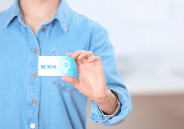 Photo of Girl holding medical business card indoors, closeup with space for text. Women's health service