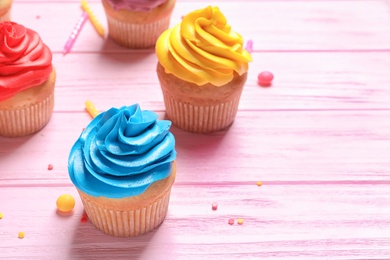 Photo of Delicious birthday cupcakes on wooden background